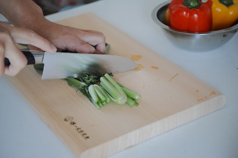 一文字光秀の銀杏木まな板で野菜をカットする様子、日本製の刃に優しい木製カッティングボード
